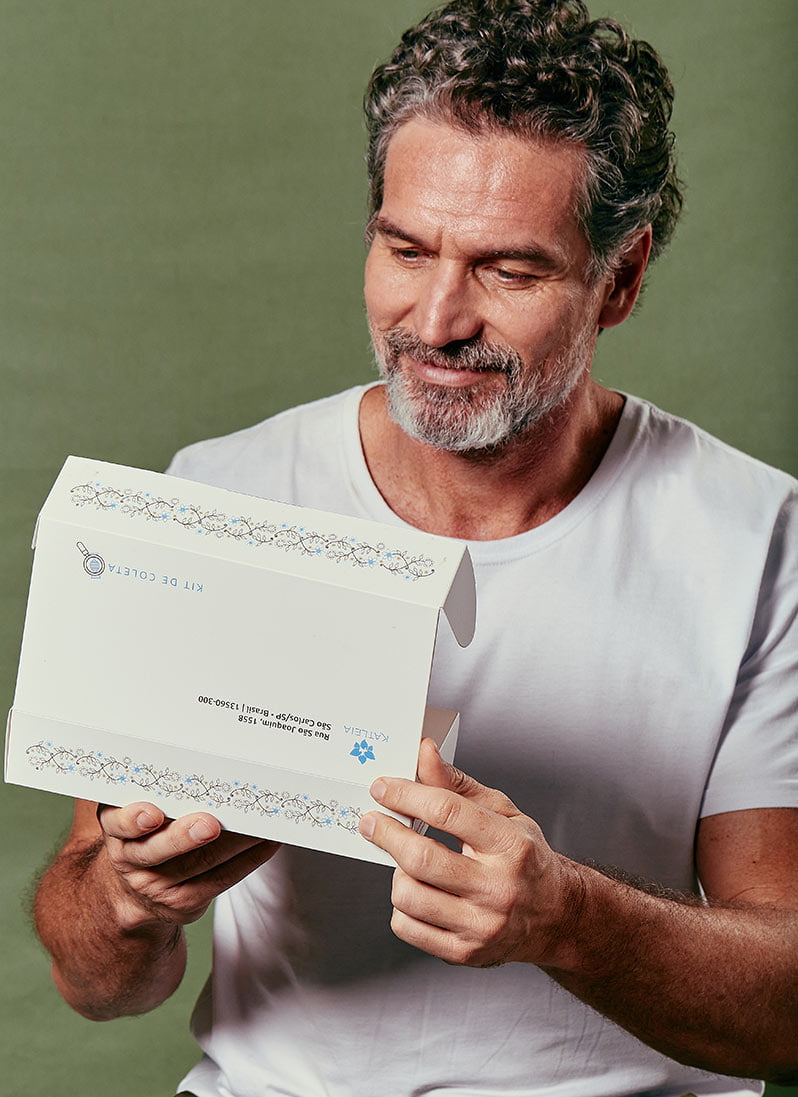 Homem de meia-idade abrindo o envelope com os resultados da Katléia